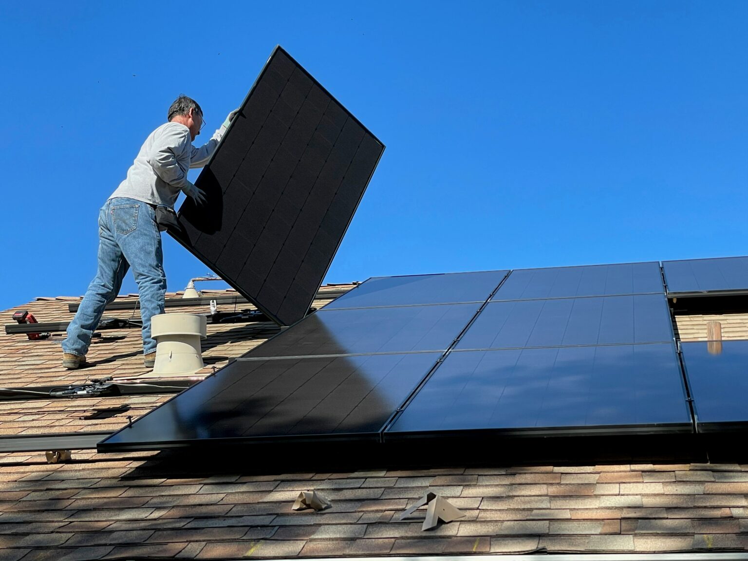 Person montiert Solarpanel auf Dach.
