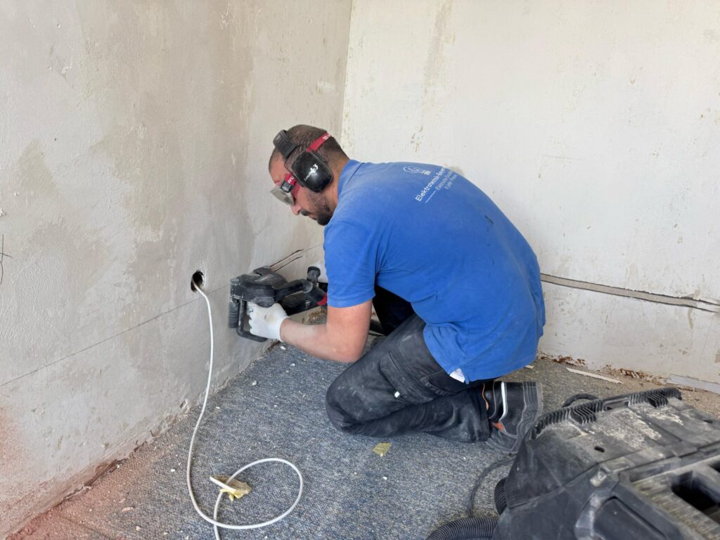 Elektriker bohrt Kabelkanal in Wand mit Bohrmaschine