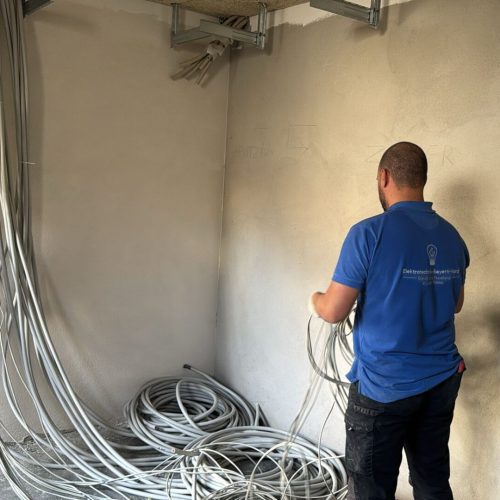 Elektriker verlegt Kabel an einer Wand