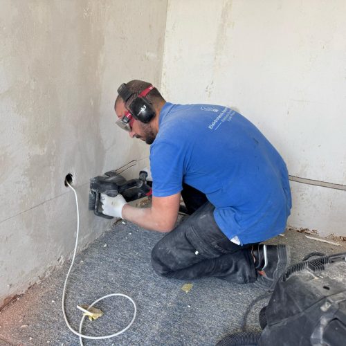Elektriker bohrt Kabelkanal in Wand mit Bohrmaschine